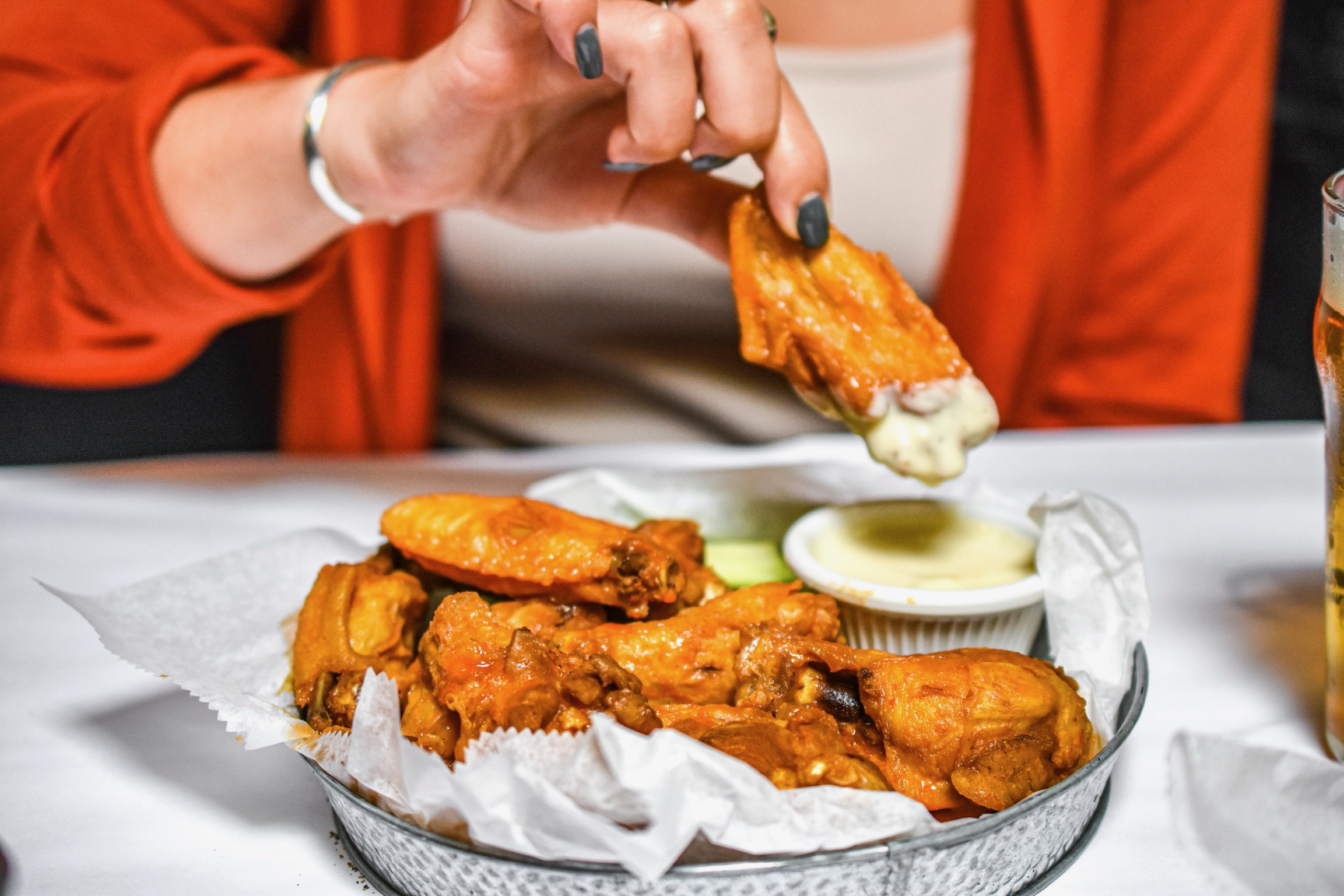 A hand dipping the best wings in town in ranch dressing