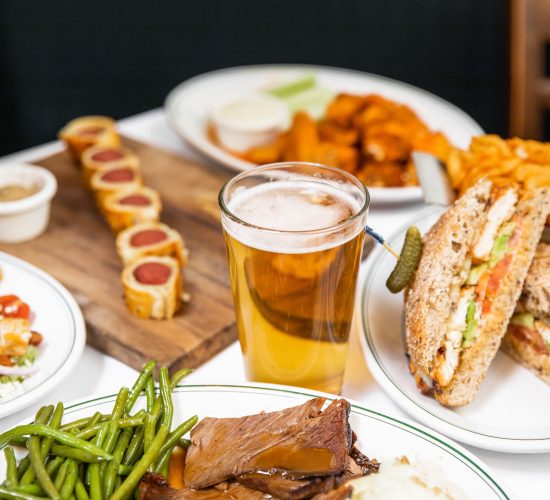 A table with sandwiches, beer, wings, and American food